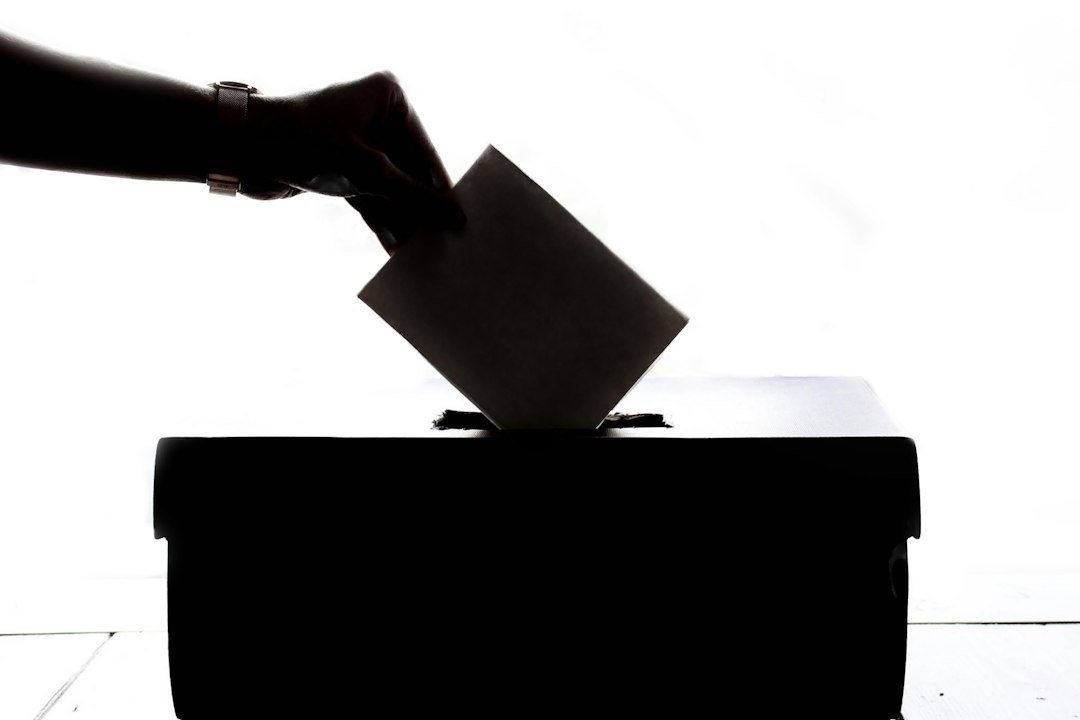 A person casting a ballot into a voting box, representing election integrity and voter participation